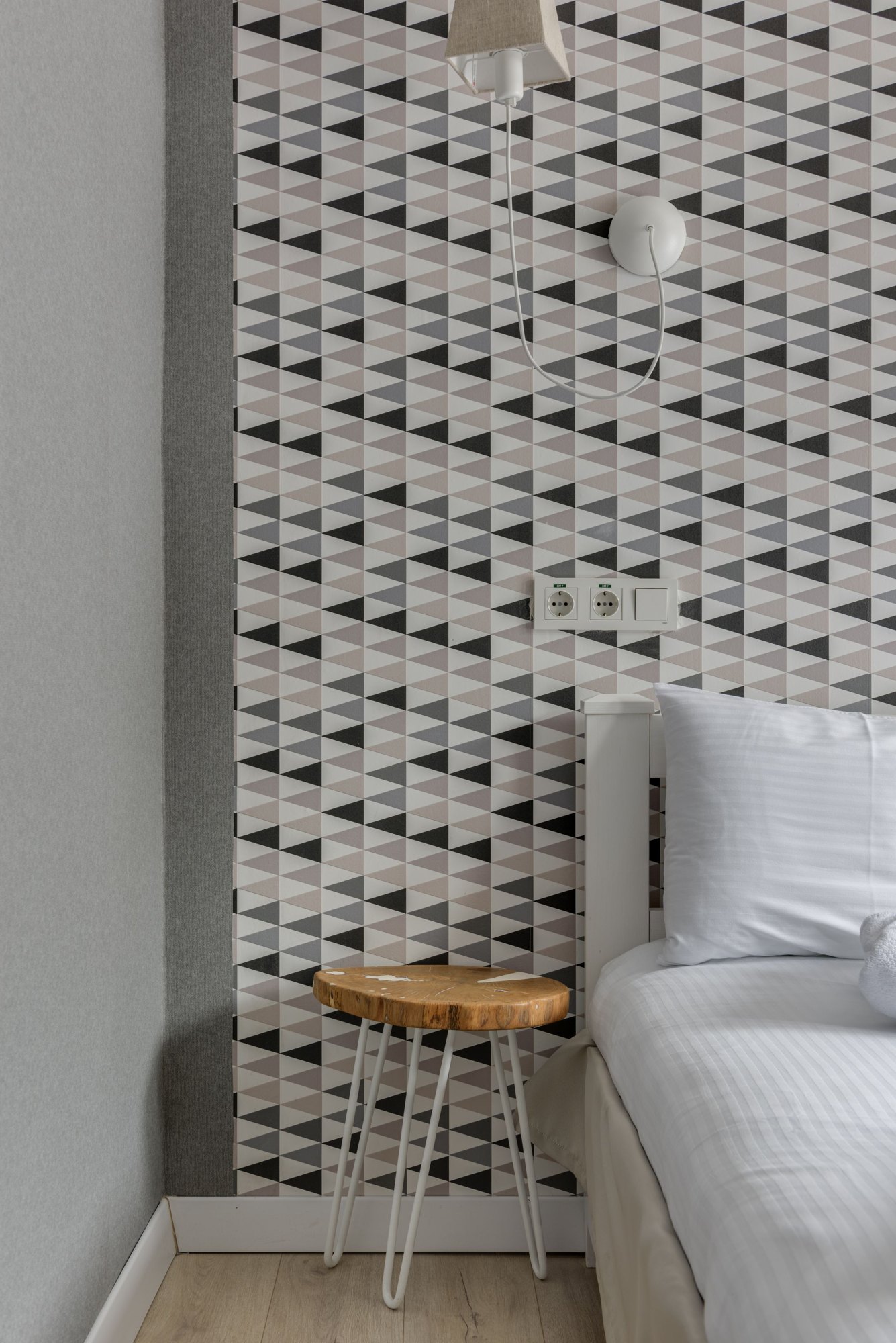 Close view of geometric wallpaper above a wooden bedside table